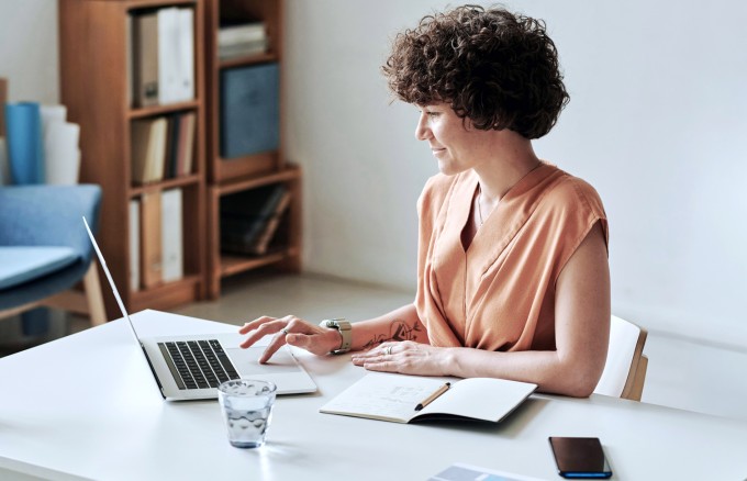 Frau sitzt am Schreibtisch am Laptop